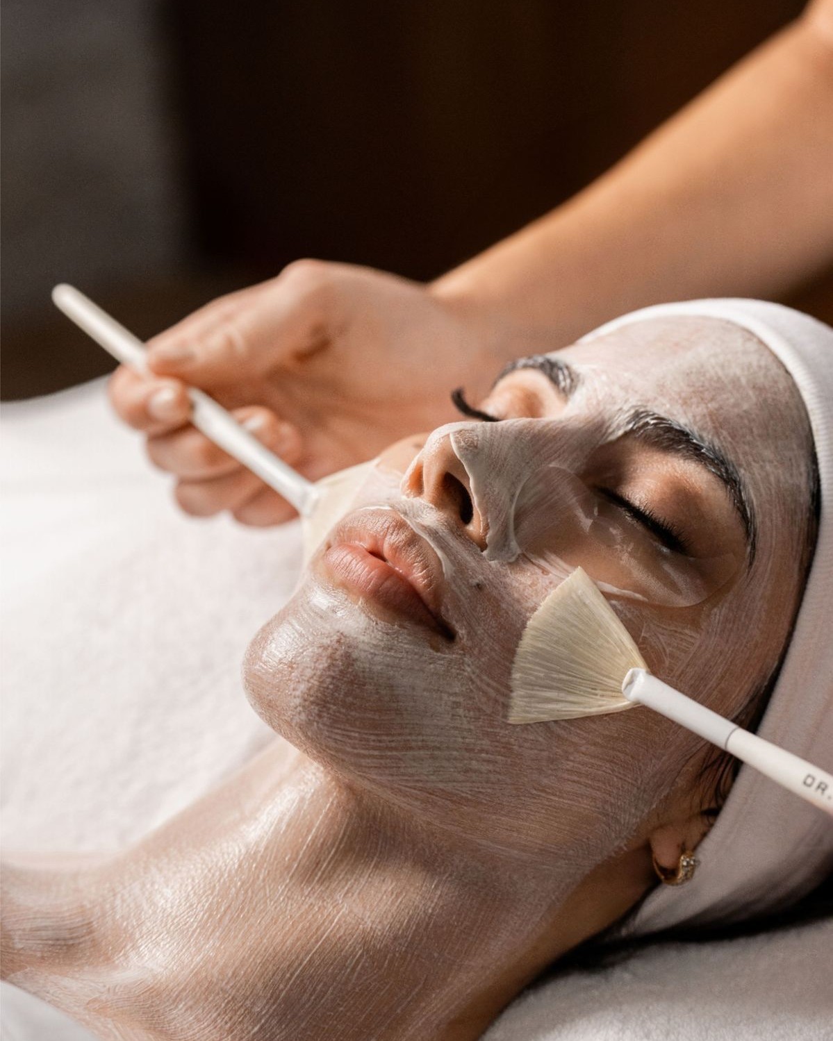 A facial mask being brushed onto a guest’s face